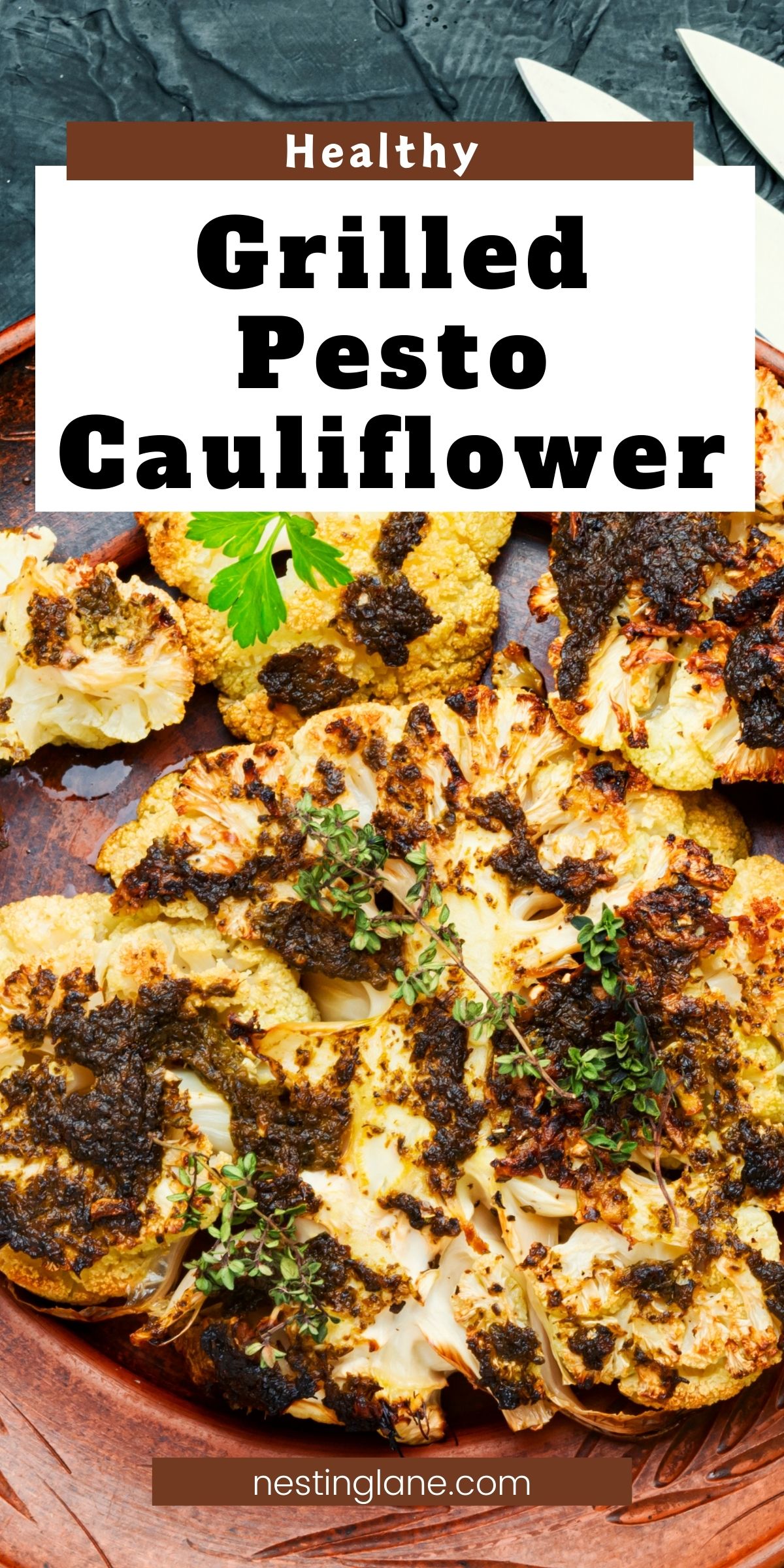 Grilled pesto cauliflower florets with charred edges, dark pesto topping, and fresh herbs on a brown plate. Text reads “Healthy,” “Grilled Pesto Cauliflower,” and “nestinglane.com.”