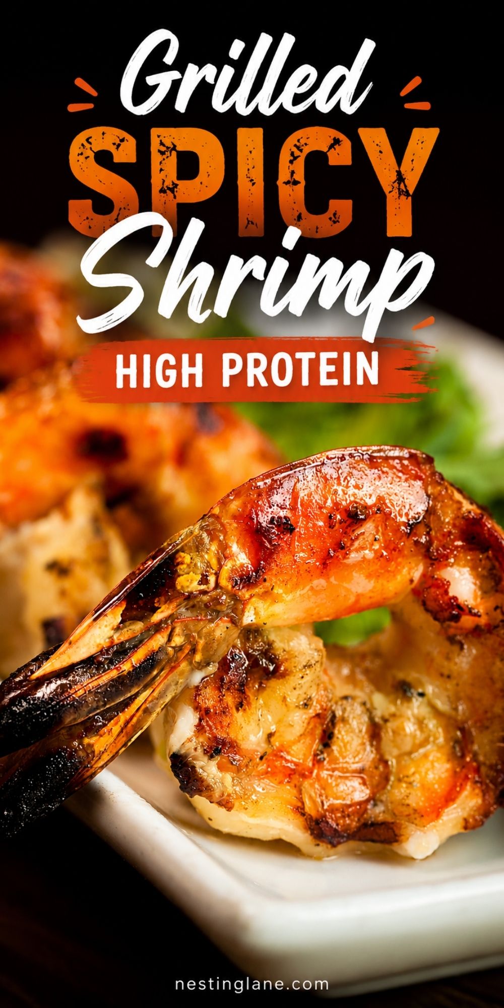 Grilled spicy shrimp with charred edges and a glossy orange sauce on a white plate, with greens blurred in the background. Text reads “Grilled Spicy Shrimp High Protein” with “nestinglane.com” at the bottom.