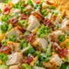 Jalapeño popper chicken chopped salad with grilled chicken, bacon, shredded cheddar, jalapeños, green onions, lettuce, creamy dressing, and tortilla chips in a speckled bowl.