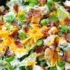 Close-up of jalapeño popper chicken salad with chopped romaine, chicken, bacon, cheddar cheese, green onions, jalapeños, and creamy dressing.