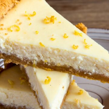 Slices of light lemon pie stacked on a plate with creamy lemon filling, graham cracker crust, and fresh lemon zest sprinkled on top.