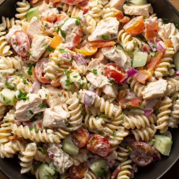 Chicken bacon ranch pasta salad with rotini, diced chicken, crispy bacon, cherry tomatoes, cucumbers, red onion, and creamy ranch dressing.