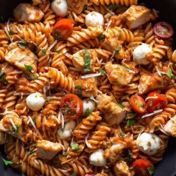 Chicken Parmesan pasta salad with rotini, diced chicken, cherry tomatoes, mozzarella pearls, shredded Parmesan, fresh basil, and tomato sauce.