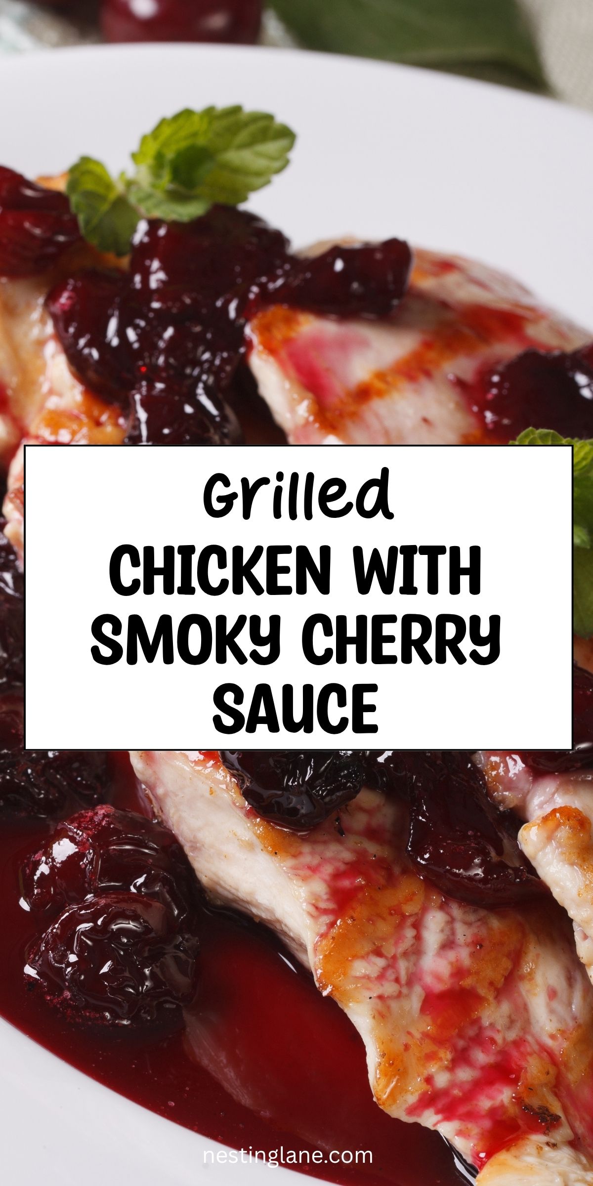 Grilled chicken topped with glossy smoky cherry sauce and fresh mint on a white plate. Text reads “Grilled Chicken with Smoky Cherry Sauce” and “nestinglane.com.”