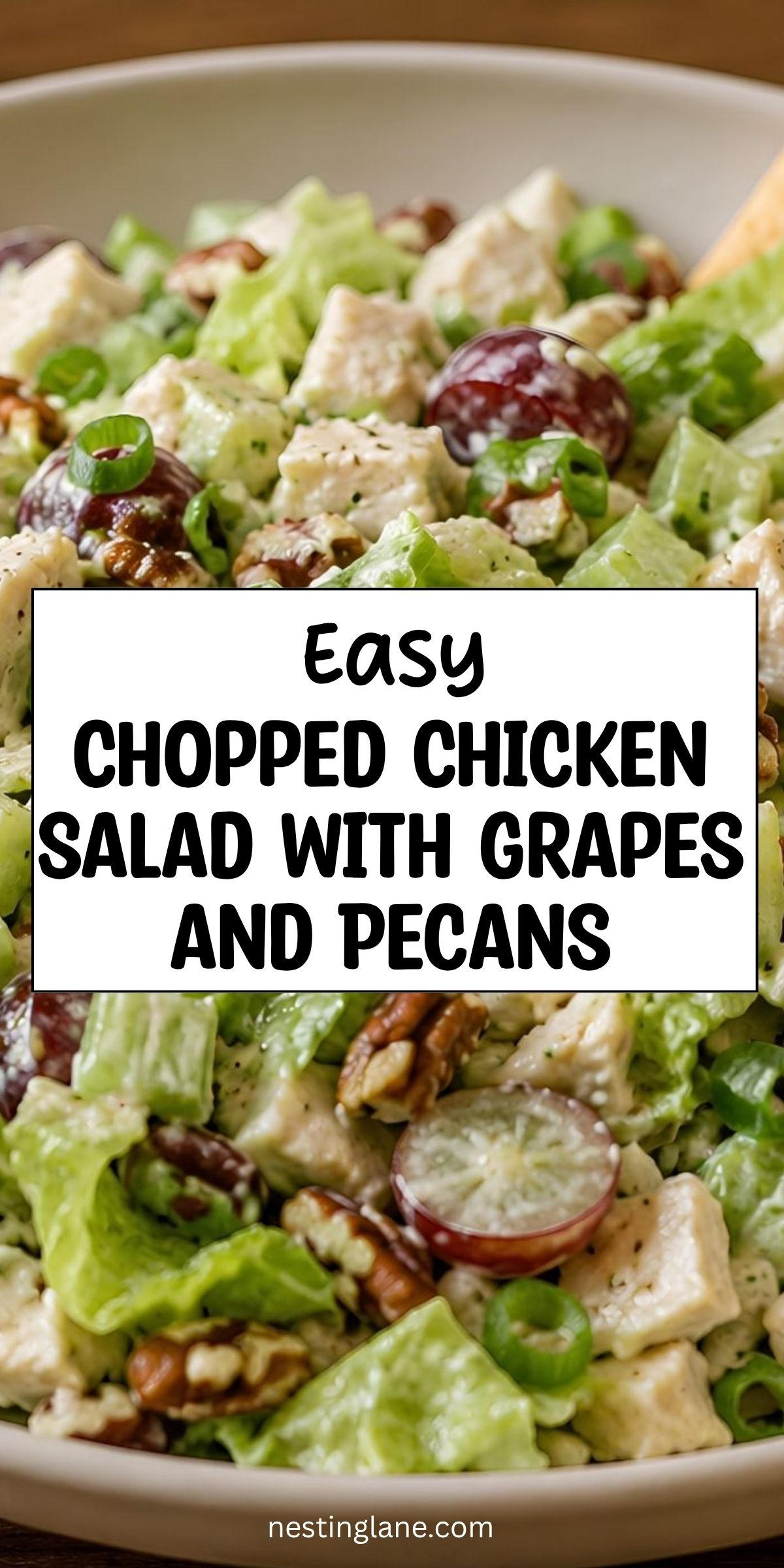 Chopped chicken salad with grapes, pecans, lettuce, green onions, and creamy dressing in a white bowl. Text reads “Easy Chopped Chicken Salad with Grapes and Pecans” and “nestinglane.com.”
