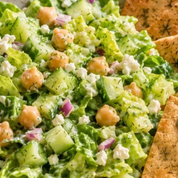 Creamy cucumber dill chickpea salad with chopped romaine, cucumber, chickpeas, red onion, feta, fresh dill, and creamy dressing, served in a bowl with toasted pita chips.