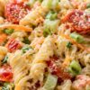 Creamy ranch vegetable pasta salad with rotini pasta, cherry tomatoes, broccoli, carrots, cucumber, green onions, and creamy ranch dressing in a close-up bowl.
