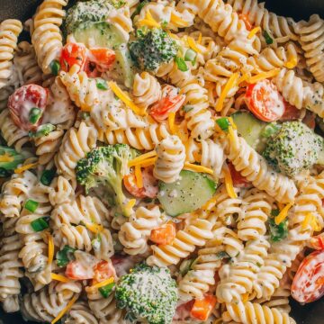 Close-up of creamy ranch pasta salad with rotini, broccoli, cucumbers, tomatoes, bell peppers, cheddar cheese, and ranch dressing.