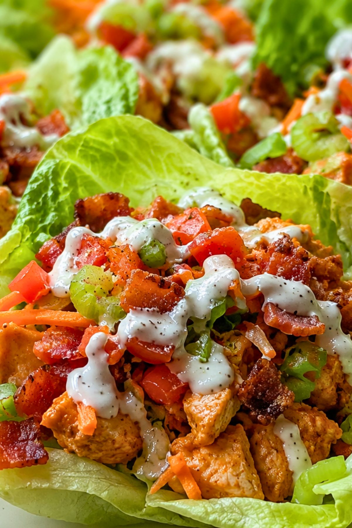 Crispy Buffalo chicken BLT lettuce wraps with chopped chicken, bacon, tomato, celery, carrots, green onions, and creamy ranch dressing piled into fresh lettuce cups.