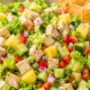 Hawaiian chicken chopped salad with romaine lettuce, diced chicken, pineapple, cucumber, red bell pepper, red onion, green onion, and crispy wonton chips in a shallow bowl.