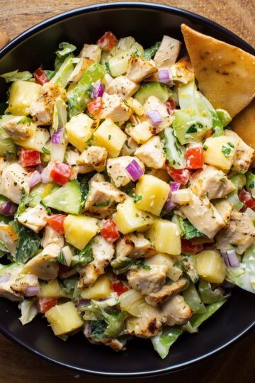 Hawaiian chicken chopped salad with grilled chicken, pineapple, cucumbers, lettuce, red bell peppers, red onion, and crispy chips.