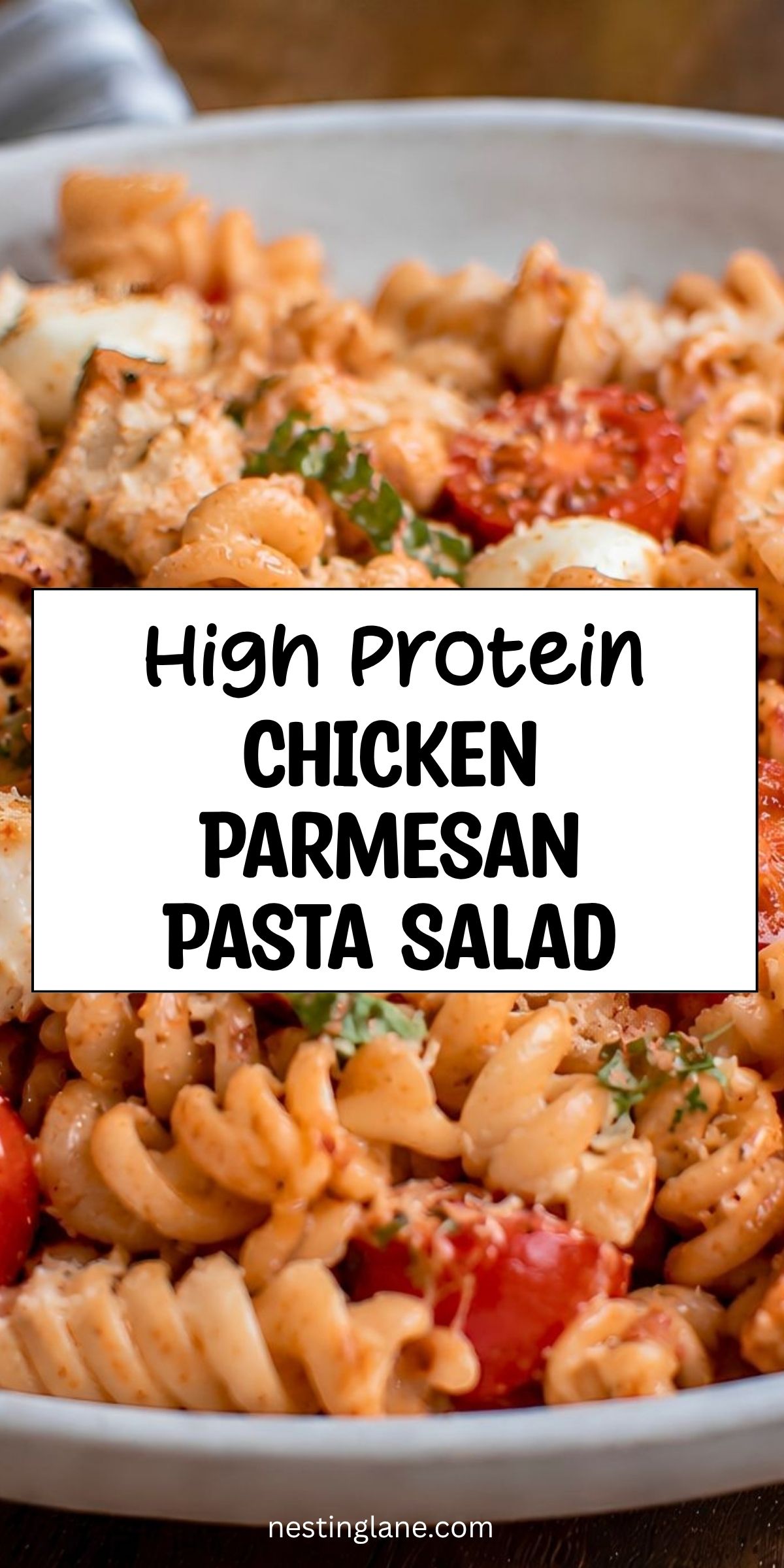 High protein chicken Parmesan pasta salad with rotini, chicken, tomatoes, mozzarella, basil, and Parmesan. Text reads “High Protein Chicken Parmesan Pasta Salad” and “nestinglane.com.”
