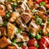 Hot honey chicken sweet potato bowl with grilled chicken, roasted sweet potatoes, corn, red peppers, cherry tomatoes, green onions, romaine, and creamy sauce.