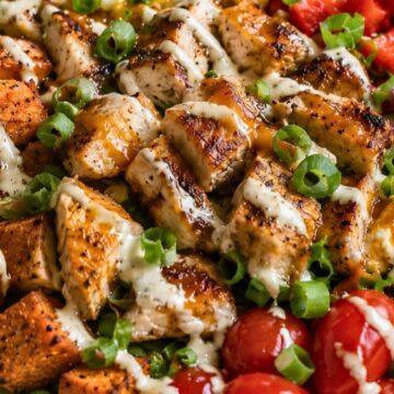 Hot honey chicken sweet potato bowl with grilled chicken, roasted sweet potatoes, corn, red peppers, cherry tomatoes, green onions, romaine, and creamy sauce.