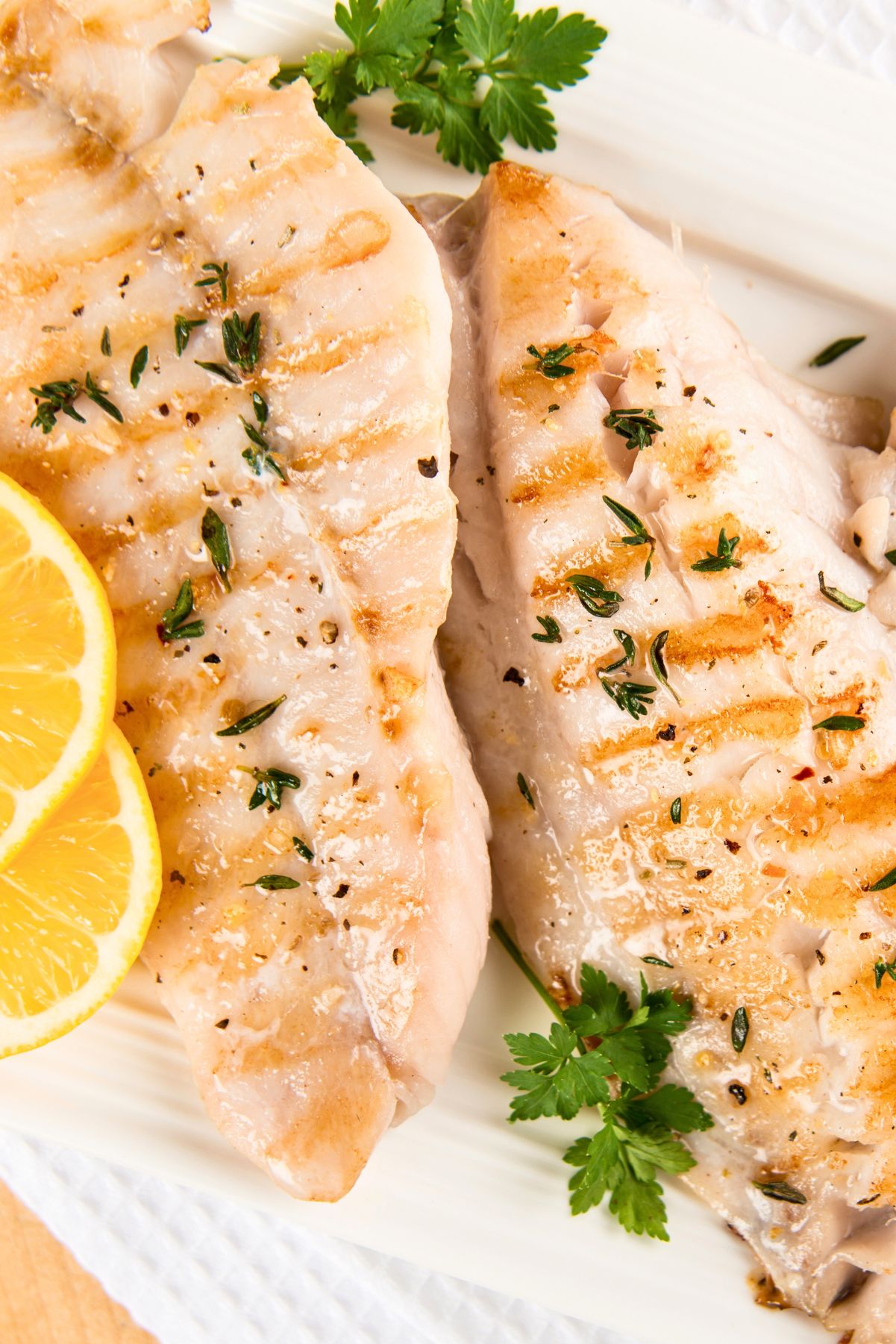 Grilled Lemon Herb White Fish Fillets on a white background.