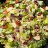 Close-up of apple pecan salad with crisp lettuce, apples, pecans, dried cranberries, celery, and creamy cider dressing.