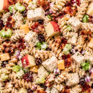 Chicken bacon apple pasta salad with whole wheat rotini, chopped chicken, crispy bacon, red apples, celery, cheddar cheese, dried cranberries, red onion, and creamy Dijon dressing.