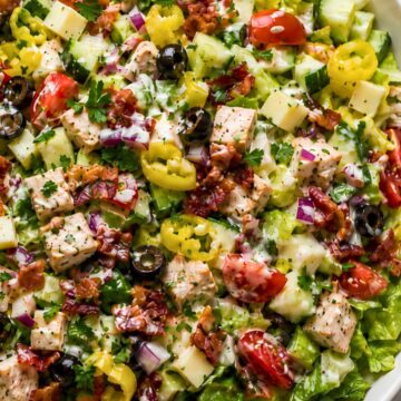 Chicken bacon grinder chopped salad with romaine, seasoned chicken breast, turkey bacon, provolone, cucumbers, cherry tomatoes, banana peppers, black olives, red onion, parsley, and creamy grinder dressing.