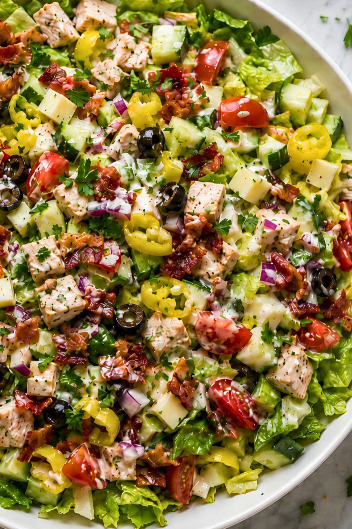 Chicken bacon grinder chopped salad with romaine, seasoned chicken breast, turkey bacon, provolone, cucumbers, cherry tomatoes, banana peppers, black olives, red onion, parsley, and creamy grinder dressing.