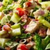 Close-up of chicken bacon grinder chopped salad with chicken, crispy bacon, romaine lettuce, cucumbers, cherry tomatoes, red onion, black olives, and creamy dressing.