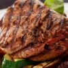 Grilled sirloin steak with dark grill marks served over sliced zucchini and eggplant, with roasted red pepper and chunky balsamic tomato-onion jam on a white plate.