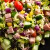 Ham and provolone grinder chopped salad with diced ham, provolone, lettuce, cucumbers, tomatoes, red onion, banana peppers, black olives, and creamy dressing.