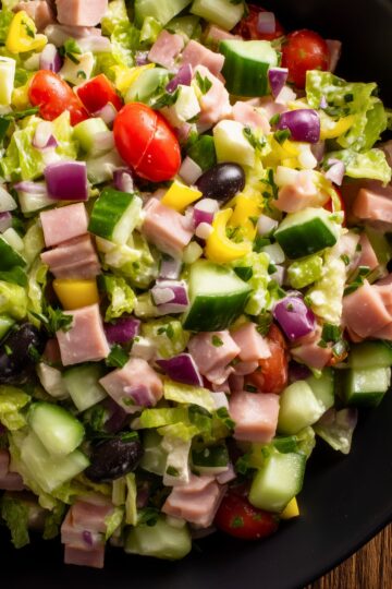 Ham and provolone grinder chopped salad with diced ham, provolone, lettuce, cucumbers, tomatoes, red onion, banana peppers, black olives, and creamy dressing.