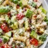 High protein Chicken Cobb pasta salad with rotini, grilled chicken, turkey bacon, avocado, cherry tomatoes, cucumber, romaine, hard-boiled eggs, blue cheese crumbles, red onion, and creamy dressing.