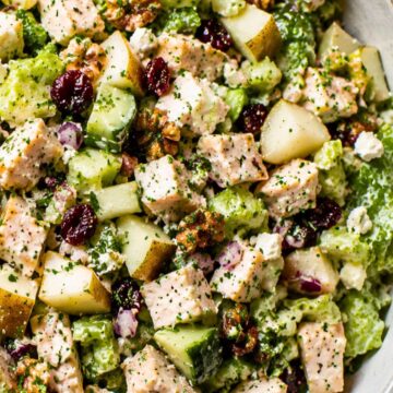 Close-up of pear walnut chicken chopped salad with romaine lettuce, cucumber, celery, diced pear, dried cranberries, red onion, feta cheese, walnuts, and chicken tossed in creamy balsamic Dijon dressing.