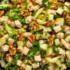 Close-up of pear walnut chicken chopped salad with diced chicken, pears, crunchy walnuts, dried cranberries, lettuce, and creamy dressing.