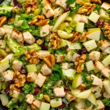 Close-up of pear walnut chicken chopped salad with diced chicken, pears, crunchy walnuts, dried cranberries, lettuce, and creamy dressing.