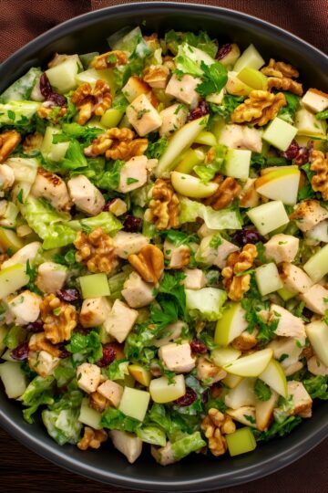 Close-up of pear walnut chicken chopped salad with diced chicken, pears, crunchy walnuts, dried cranberries, lettuce, and creamy dressing.