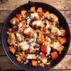 Cajun chicken sweet potato bowl with roasted chicken, sweet potatoes, black beans, corn, red and green bell peppers, and creamy Cajun yogurt sauce in a black bowl on rustic wood.