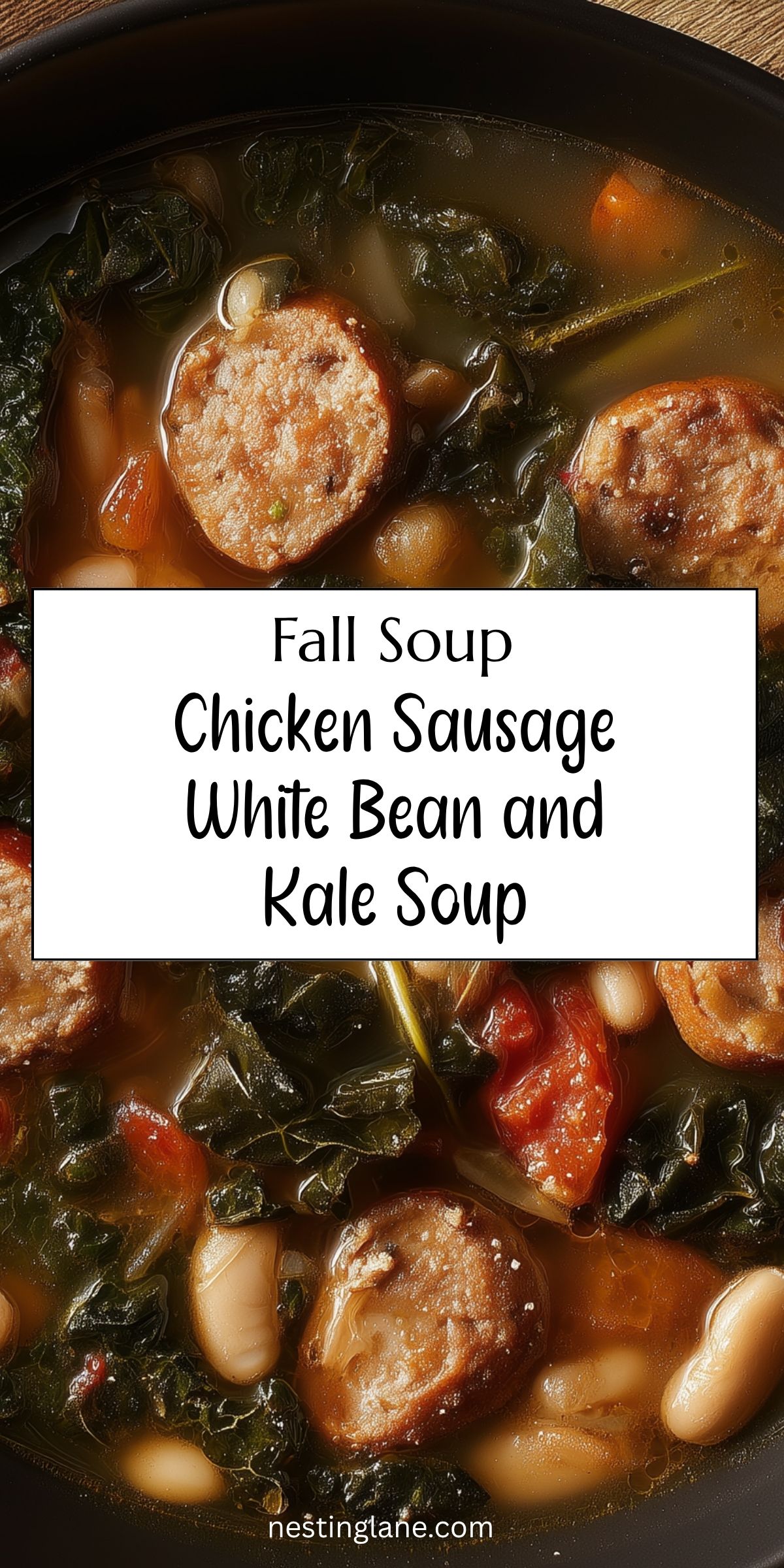 Overhead close-up of chicken sausage, white bean and kale soup with sliced sausage, cannellini beans, carrots, tomatoes and leafy kale in broth. Text reads: “Fall Soup Chicken Sausage White Bean and Kale Soup” and “nestinglane.com.”