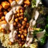 Chickpea Sweet Potato Protein Bowl with roasted sweet potatoes, crispy chickpeas, broccoli, quinoa, and fresh spinach in a black bowl, topped with a creamy sauce.