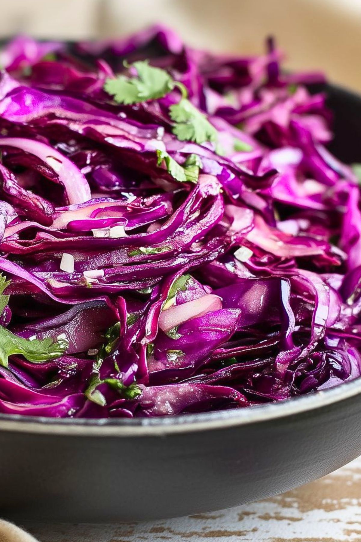 Crunchy red cabbage lime slaw with thinly sliced purple cabbage, red onion, and fresh cilantro tossed in a light lime dressing and served in a black bowl.