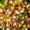 Fall chicken chopped salad with diced chicken, apples, sweet potatoes, dried cranberries, pecans, mixed greens, and creamy dressing.