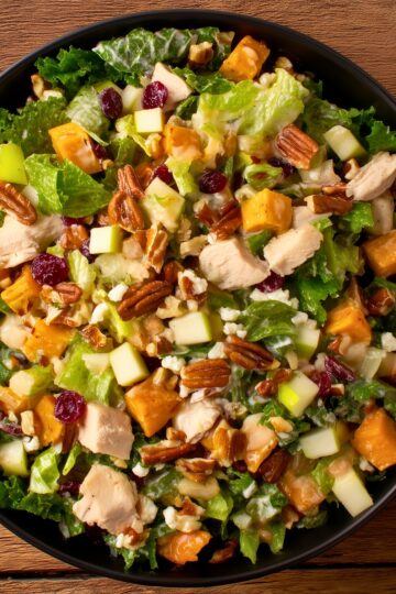 Fall chicken chopped salad with diced chicken, apples, sweet potatoes, dried cranberries, pecans, mixed greens, and creamy dressing.
