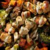 Garlic Parmesan chicken sweet potato bowl with roasted chicken breast, sweet potato chunks, broccoli, herbs, and creamy Parmesan sauce in a black bowl.