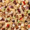 Creamy healthy apple pecan pasta salad with whole wheat rotini, chopped red apples, celery, dried cranberries, pecans, red onion, feta cheese, and herbs in a creamy dressing.