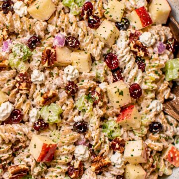 Creamy healthy apple pecan pasta salad with whole wheat rotini, chopped red apples, celery, dried cranberries, pecans, red onion, feta cheese, and herbs in a creamy dressing.