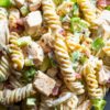 Close-up of high protein jalapeño popper chicken pasta salad with rotini, chunks of chicken breast, turkey bacon, green onions, jalapeños, and creamy dressing with black pepper seasoning.