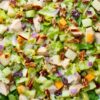 Close-up of maple Dijon chicken chopped salad with chicken, apples, pecans, cranberries, cheddar cheese, red onion, and chopped lettuce.