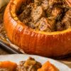 Roasted pumpkin stuffed with tender braised pork in a rich savory sauce, with a serving of pork and roasted pumpkin pieces plated in the foreground.