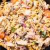 Southwest chicken pasta salad with rotini, chicken, black beans, corn, cherry tomatoes, red onion, cilantro, and creamy dressing in a black bowl.