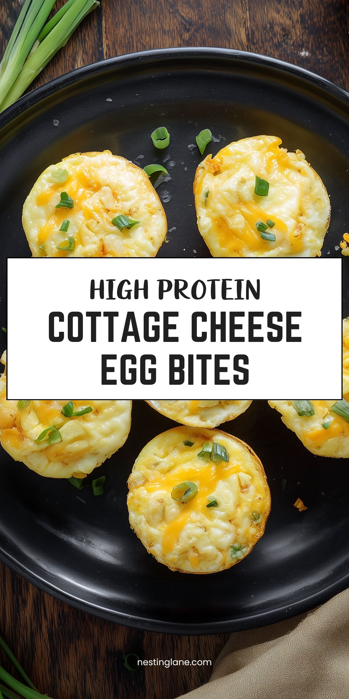 High protein cottage cheese egg bites topped with melted cheddar and green onions on a black plate. Text reads “HIGH PROTEIN COTTAGE CHEESE EGG BITES” and “nestinglane.com.”