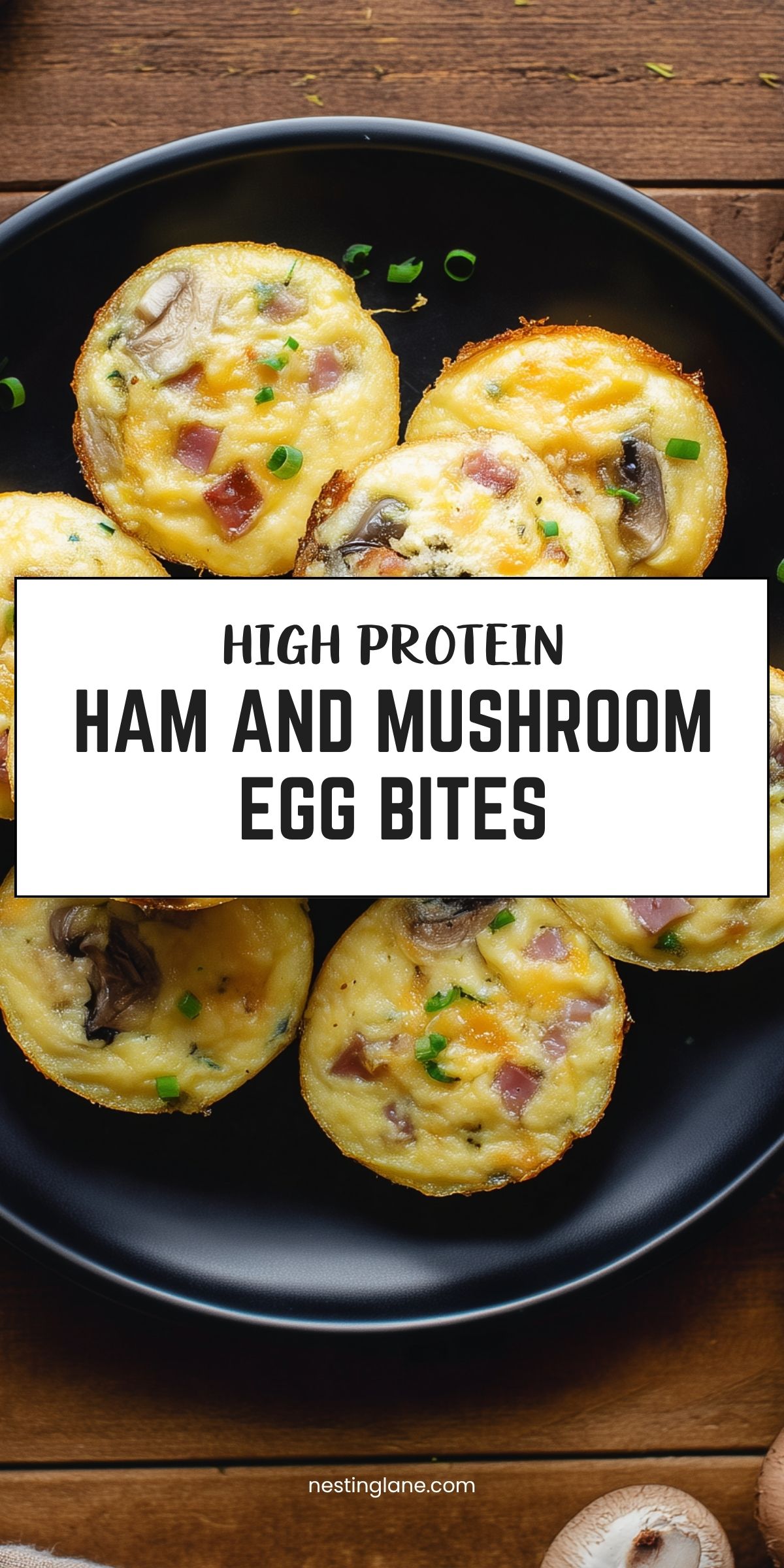 Pinterest graphic with ham and mushroom egg bites on a black plate over a rustic wood table. Text reads: “HIGH PROTEIN HAM AND MUSHROOM EGG BITES” and “nestinglane.com.”