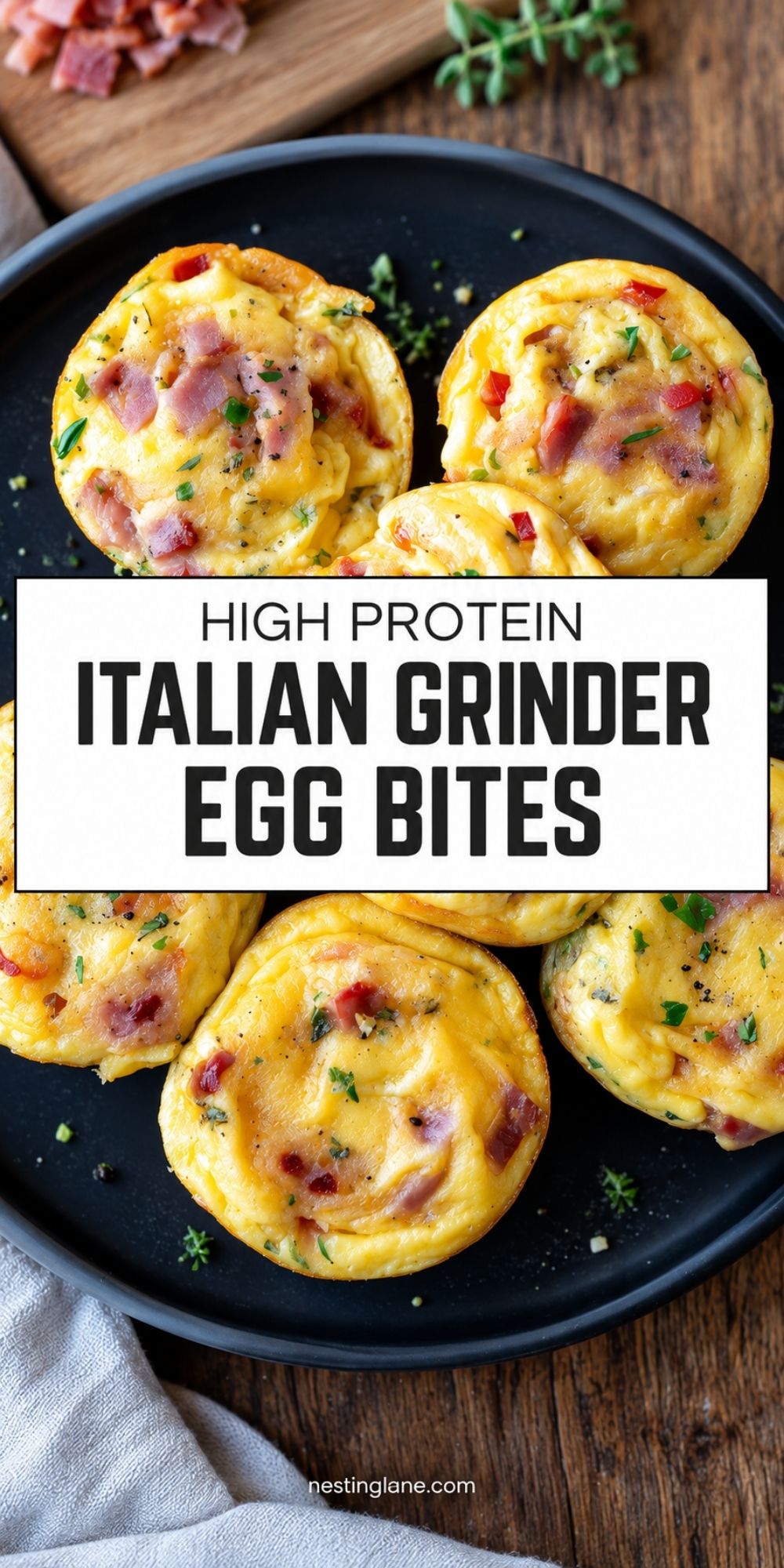 Pinterest pin with Italian grinder egg bites filled with ham, cheese, and peppers on a black plate. Text reads “High Protein Italian Grinder Egg Bites” and “nestinglane.com.”