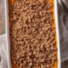 Overhead view of maple pecan sweet potato casserole in a white baking dish, with orange sweet potato filling covered in a generous brown sugar pecan crumble topping.