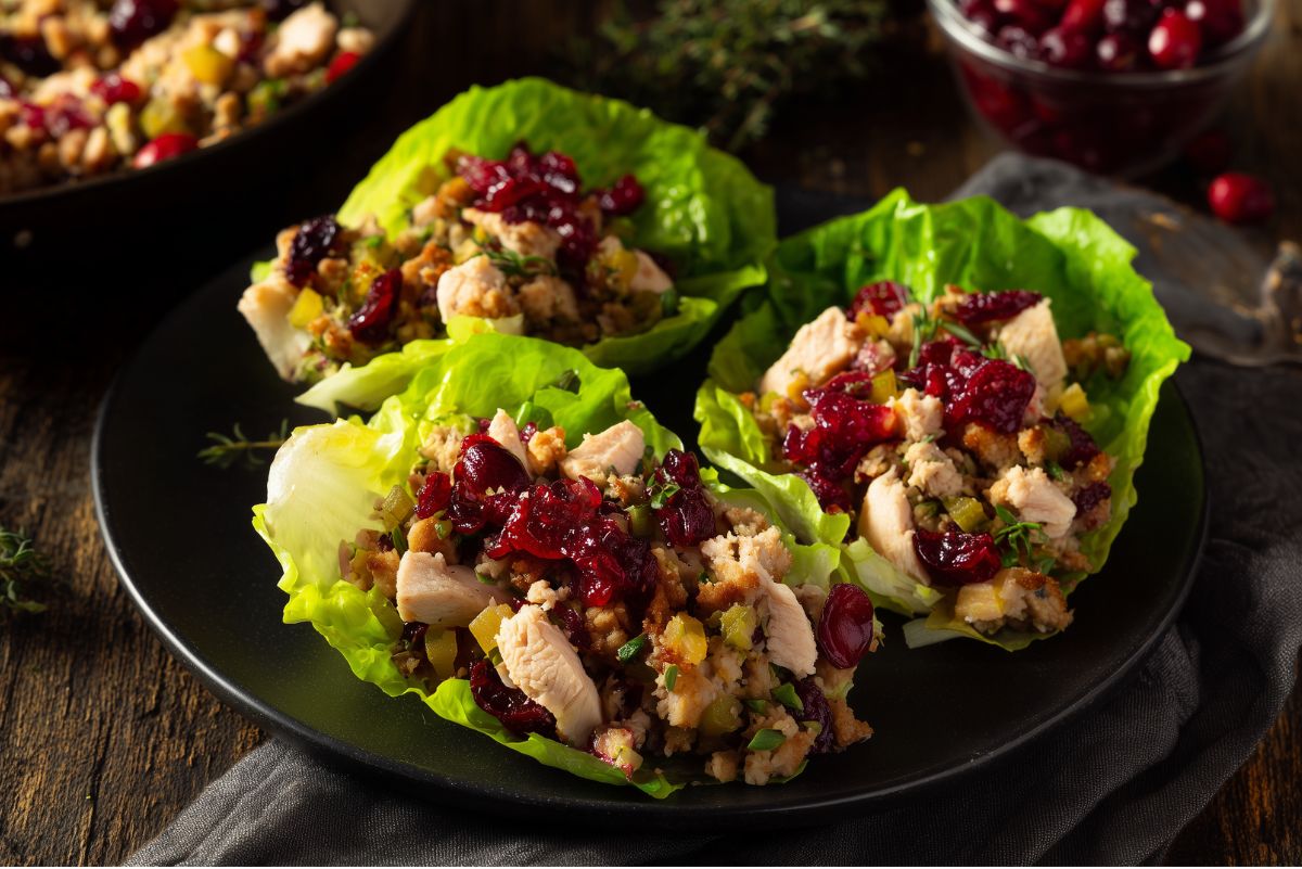 Turkey cranberry stuffing lettuce wraps filled with roasted turkey, savory stuffing, celery, dried cranberries, and cranberry sauce in crisp lettuce cups, served on a black plate for an easy Thanksgiving leftovers meal.